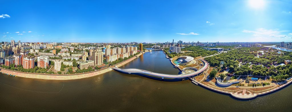 NUR-SULTAN, KAZAKHSTAN - July 30, 2019: Beautiful panoramic aerial drone view to Ishim River Embankment and Nursultan (Astana) city center with skyscrapers and modern pedestrian bridge